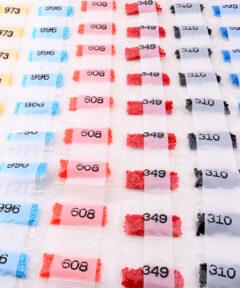 Bolsas de Diamantes Diamond Painting 445 Colores dispuestas en filas ordenadas, mostrando bolsitas transparentes con números en negro y cuentas de colores amarillo, azul, rojo y negro.