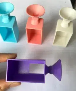 Objetos con embudos en azul, rosa y blanco sobre una superficie blanca, y un objeto púrpura sostenido por una mano, utilizados para Embudo de Diamantes Diamond