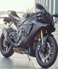 Moto deportiva negra con horquillas doradas destacando sobre un fondo urbano en una pintura de diamante.