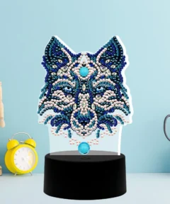 Una detallada 'Lámpara luz Decorativa Lobo Diamond Painting' con un diseño vibrante y místico de un lobo creado con cuentas brillantes de tonos azules y plateados, sobre una base negra elegante, ideal para decorar cualquier espacio con un toque mágico y moderno.