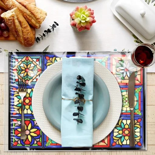 Una elegante mesa con un plato blanco texturizado y un plato celeste sobre un mantel pintura de diamantes artísticos 5D antideslizantes, acompañados por cubiertos, una servilleta celeste con ramita decorativa, copas de vino con líquido rojo, panes y uvas en una tabla de madera, una planta suculenta en maceta y una mantequillera blanca con tapa.
