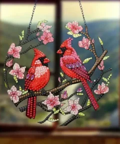 Arte colgante de dos pájaros bordados con diamantes sobre una rama con flores.